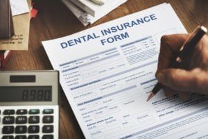 Image of a hand writing on a dental insurance form